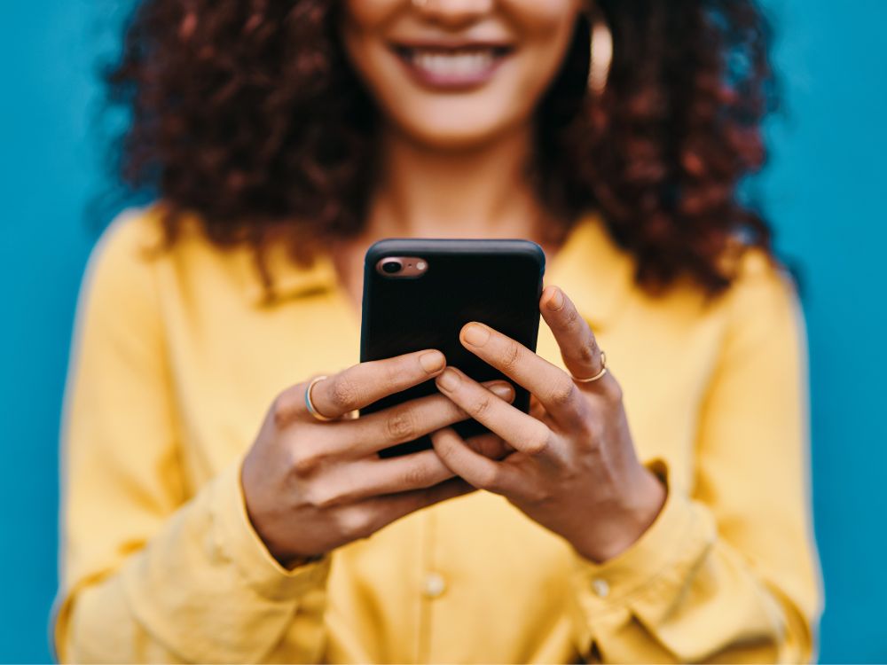 Mulher segurando o celular e buscando formas de como reconquistar o amor